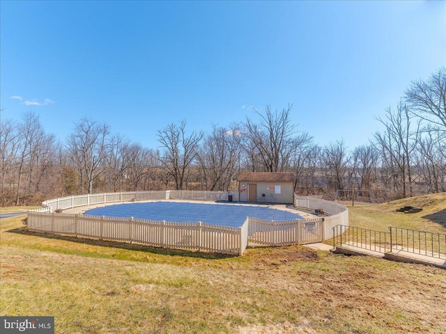 pool with a yard, an outbuilding, a patio, and fence