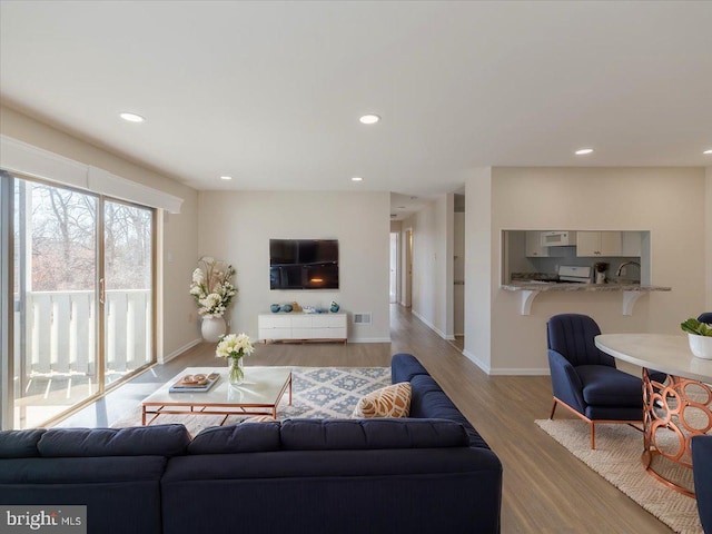 living area with recessed lighting, visible vents, baseboards, and wood finished floors