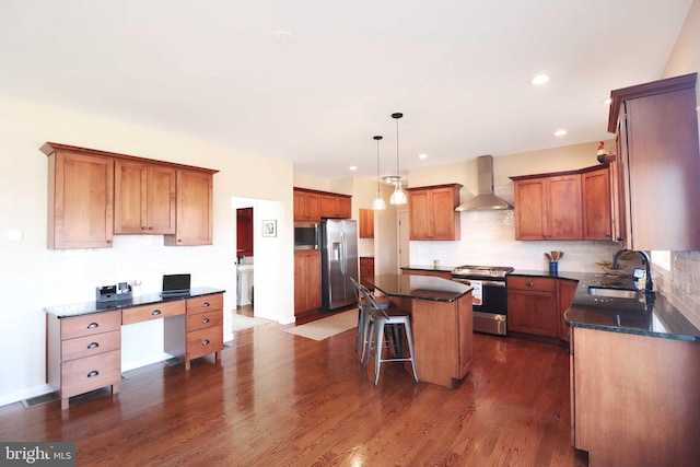 kitchen with a kitchen island, a sink, dark wood-type flooring, appliances with stainless steel finishes, and wall chimney exhaust hood