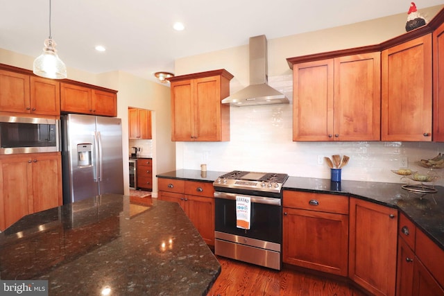 kitchen with dark wood finished floors, decorative backsplash, appliances with stainless steel finishes, wall chimney range hood, and brown cabinets