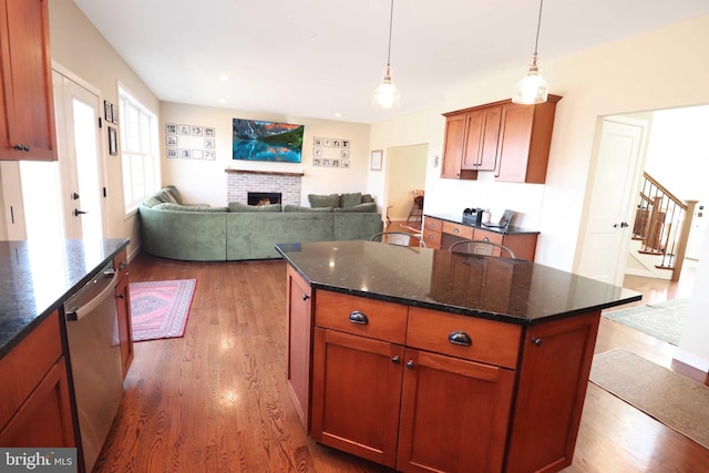 kitchen featuring a kitchen island, hanging light fixtures, a brick fireplace, dark wood-style flooring, and dishwasher