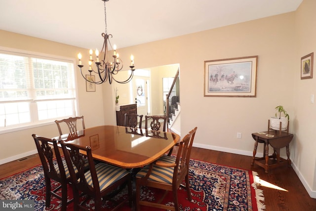 dining space featuring visible vents, baseboards, a chandelier, stairway, and wood finished floors