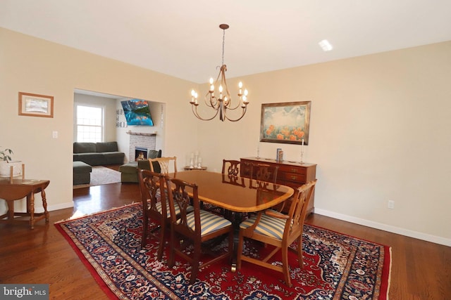 dining area with a fireplace, baseboards, and wood finished floors