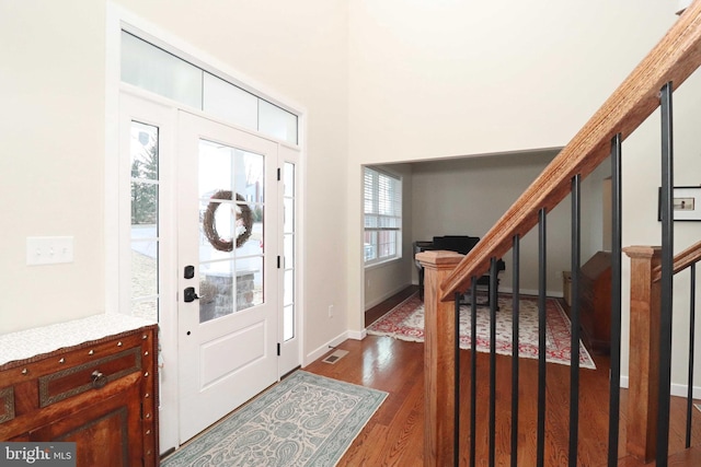 entrance foyer with stairs, dark wood-style floors, visible vents, and baseboards