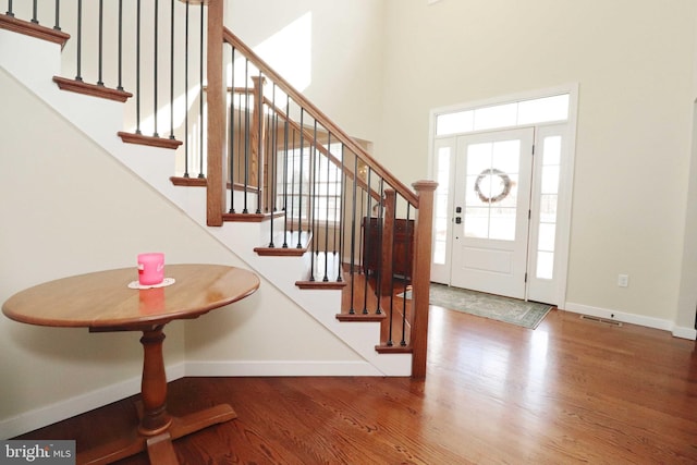 foyer entrance featuring stairway, baseboards, wood finished floors, and a towering ceiling