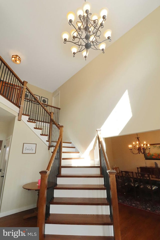 staircase featuring an inviting chandelier, wood finished floors, and baseboards