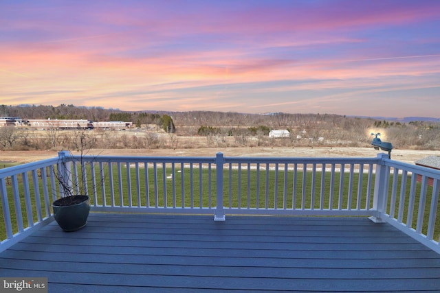 deck at dusk featuring a yard