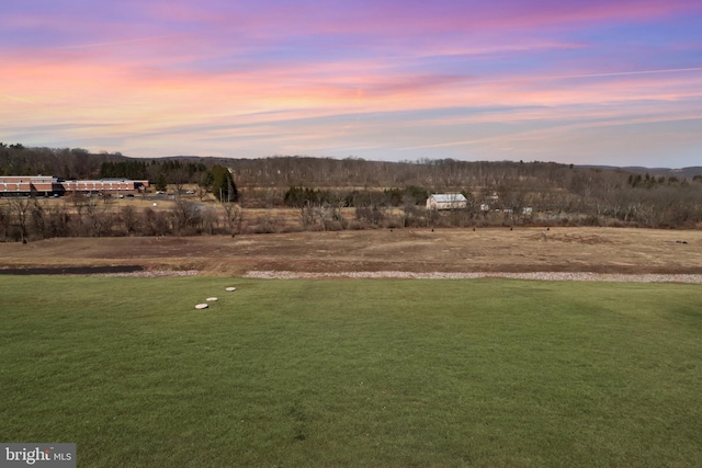 yard at dusk featuring a rural view