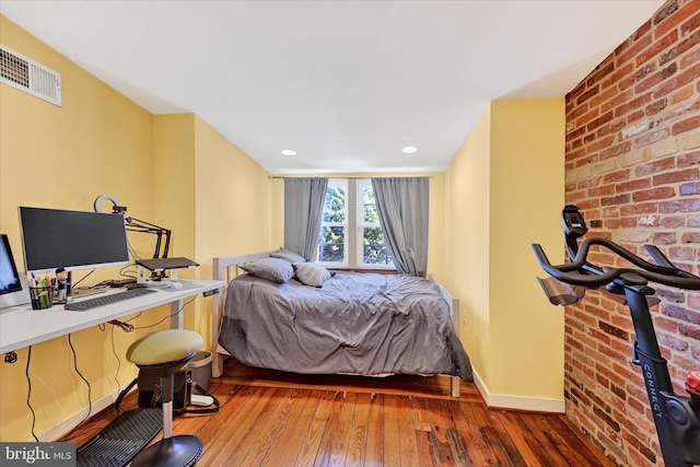 bedroom with visible vents, hardwood / wood-style flooring, recessed lighting, brick wall, and baseboards