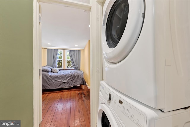 washroom with recessed lighting, stacked washer / drying machine, wood-type flooring, and laundry area