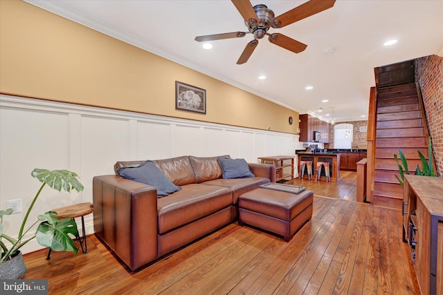 living room with crown molding, recessed lighting, wainscoting, a ceiling fan, and wood-type flooring