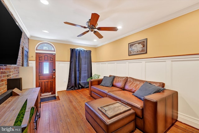 living room featuring wainscoting, hardwood / wood-style flooring, a ceiling fan, and ornamental molding