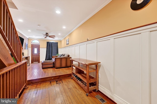 interior space featuring stairway, a wainscoted wall, visible vents, light wood finished floors, and crown molding