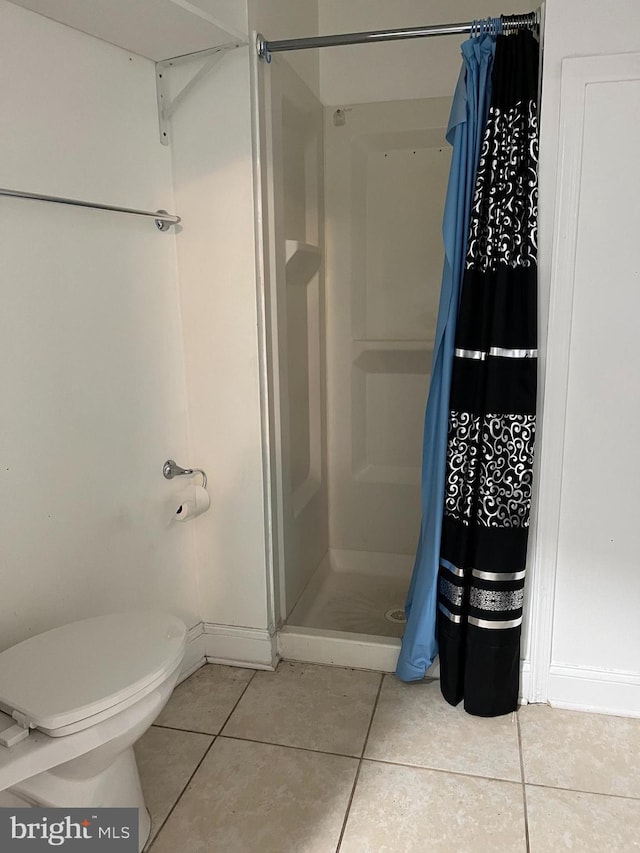 bathroom with toilet, a shower stall, and tile patterned flooring