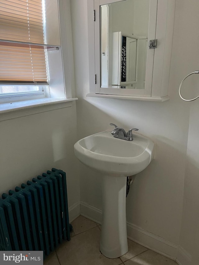 bathroom with a sink, radiator heating unit, baseboards, and tile patterned flooring