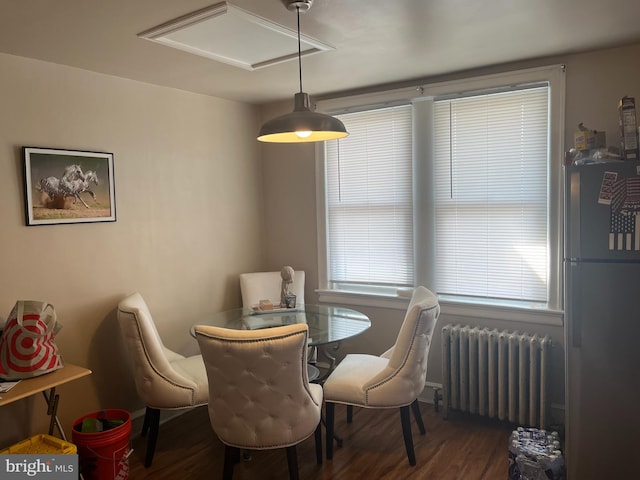 dining area with baseboards, wood finished floors, and radiator