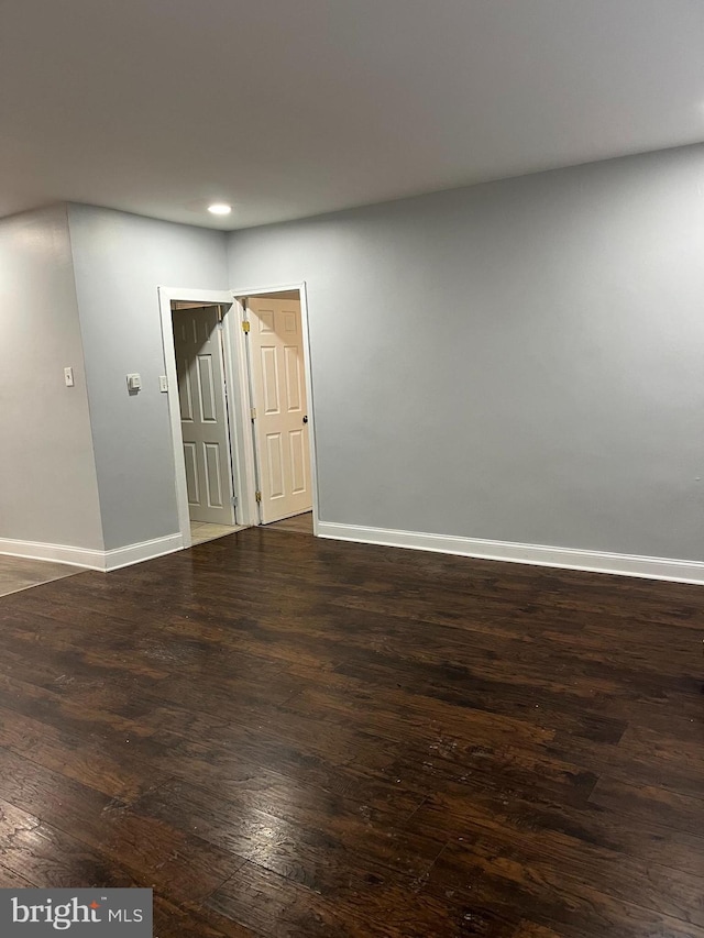 empty room featuring baseboards, dark wood-style flooring, and recessed lighting