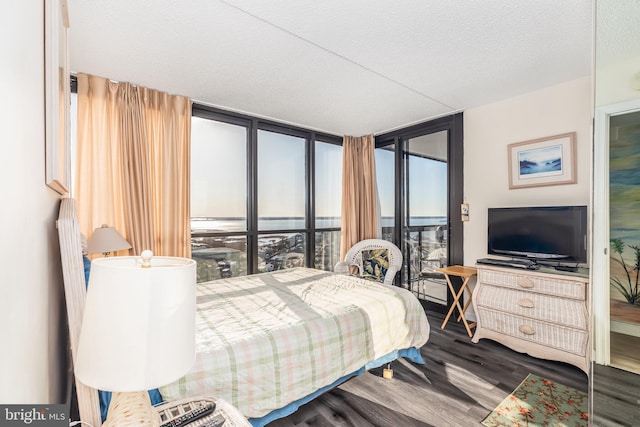 bedroom with a textured ceiling, wood finished floors, floor to ceiling windows, and access to outside