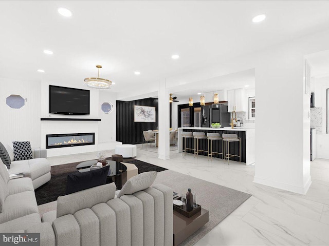 living area featuring marble finish floor, recessed lighting, baseboards, and a glass covered fireplace