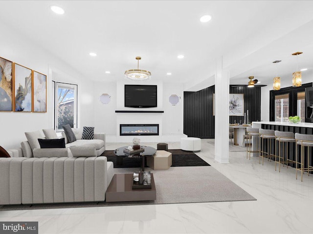 living room featuring marble finish floor, recessed lighting, and a glass covered fireplace