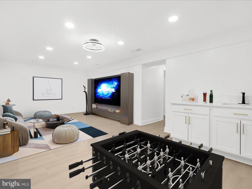 game room featuring light wood-type flooring, a sink, and recessed lighting