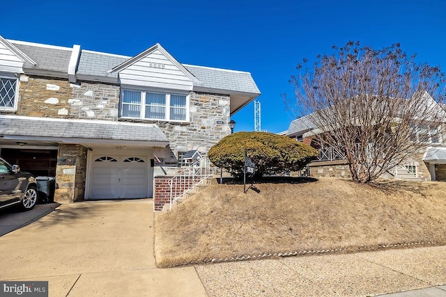 view of front of property featuring stone siding, concrete driveway, and an attached garage