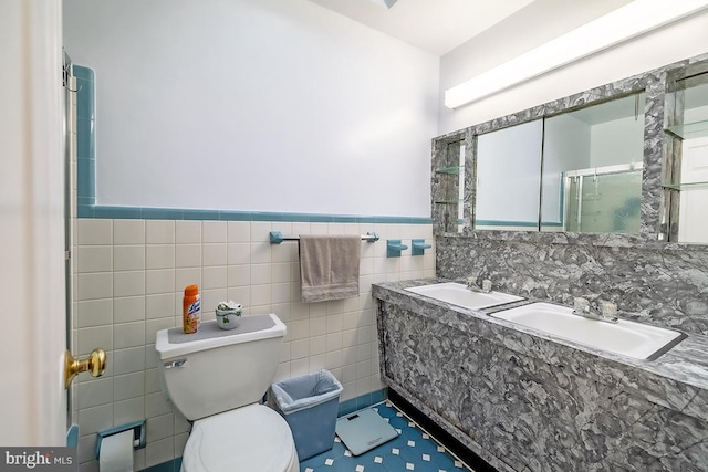 full bath with tile walls, toilet, a shower with door, and a sink