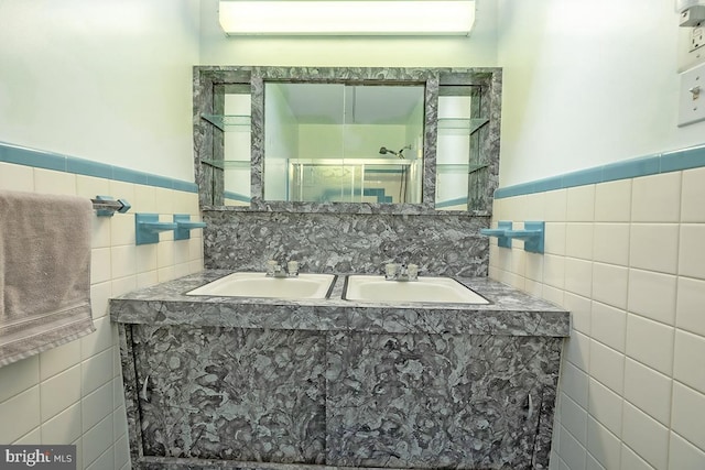 bathroom featuring double vanity, a stall shower, tile walls, and a sink