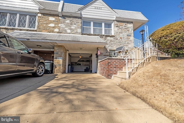 multi unit property featuring stone siding, an attached garage, concrete driveway, and stairs