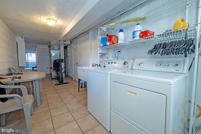 clothes washing area with a sink, separate washer and dryer, light tile patterned flooring, and laundry area