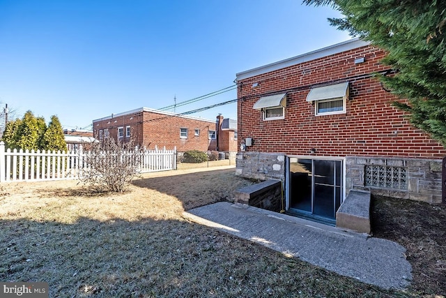 back of house featuring brick siding and fence