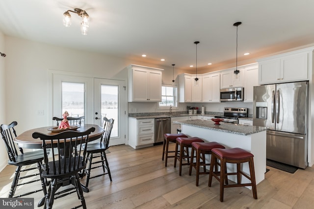 kitchen featuring white cabinets, light wood-style flooring, appliances with stainless steel finishes, and a center island