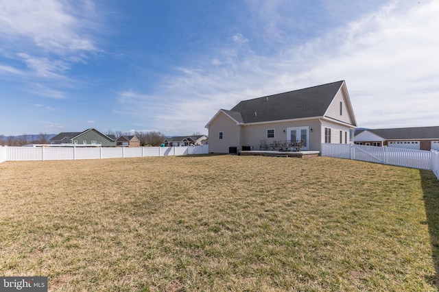 rear view of property featuring a fenced backyard, french doors, and a yard