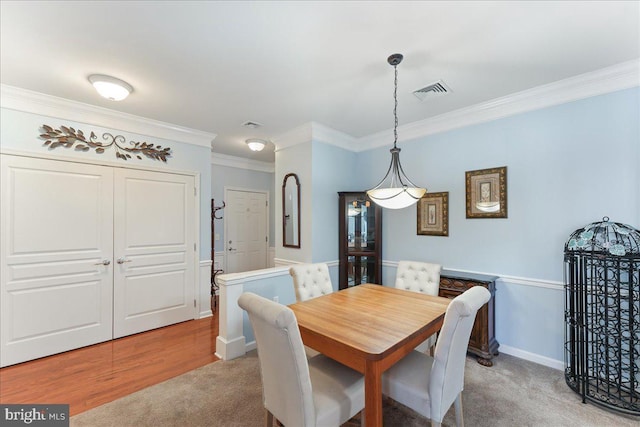 carpeted dining area with visible vents, baseboards, and crown molding