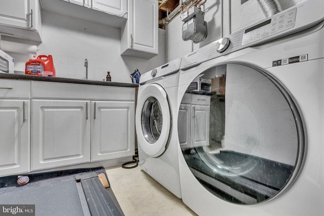 washroom with cabinet space, washer and dryer, and a sink