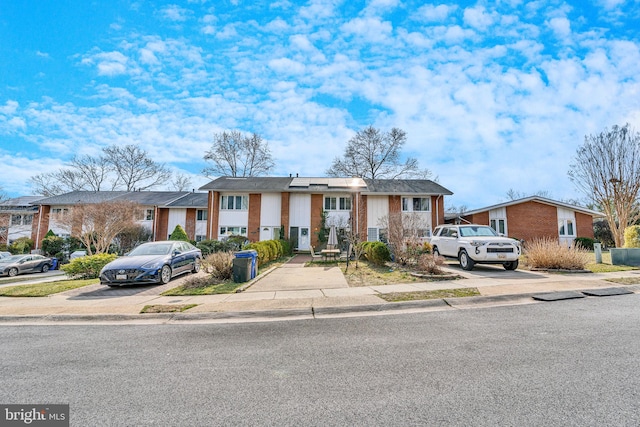 multi unit property featuring brick siding, a residential view, and driveway