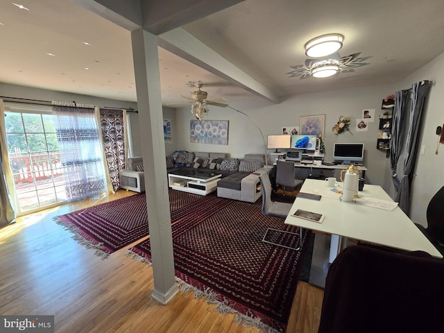 home office featuring beamed ceiling, wood finished floors, and a ceiling fan