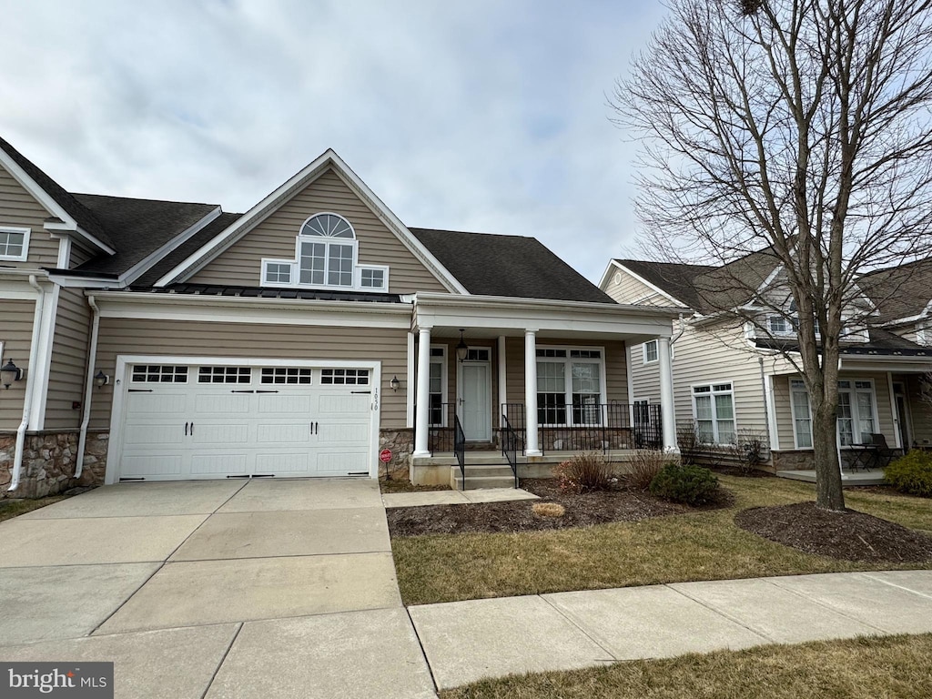 view of front of property with stone siding, a porch, and concrete driveway