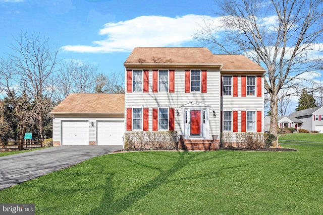 colonial house featuring aphalt driveway, a front lawn, and an attached garage