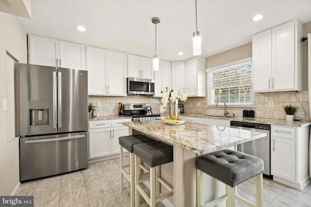 kitchen with a sink, white cabinets, backsplash, and stainless steel appliances