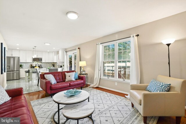 living room featuring light wood-style flooring, recessed lighting, a healthy amount of sunlight, and baseboards