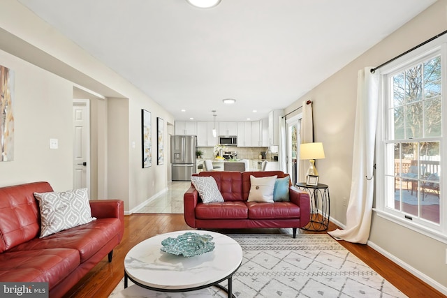 living room with plenty of natural light, baseboards, and light wood-style floors