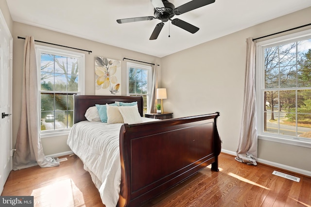 bedroom with visible vents, a ceiling fan, baseboards, and wood finished floors