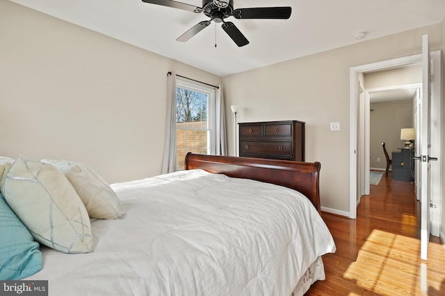 bedroom featuring baseboards, wood finished floors, and a ceiling fan