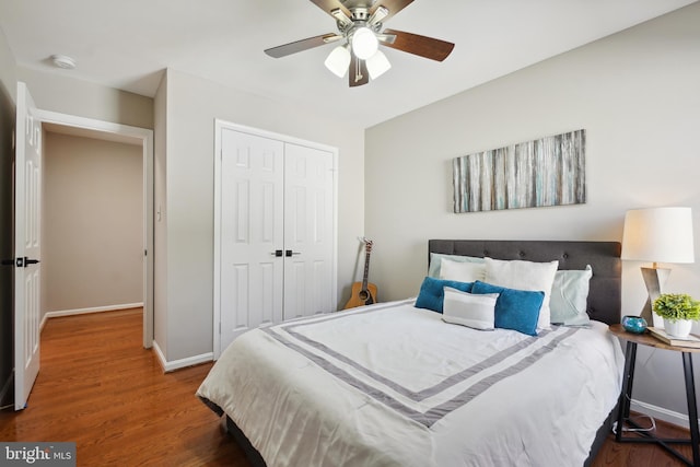 bedroom featuring ceiling fan, a closet, baseboards, and wood finished floors