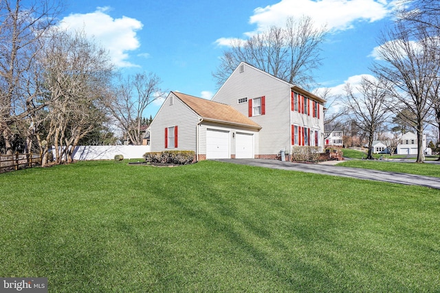 view of side of home with an attached garage, fence, a lawn, and driveway