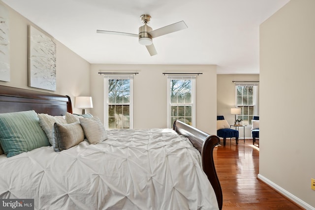 bedroom featuring hardwood / wood-style floors, a ceiling fan, and baseboards