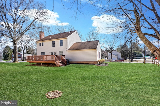 back of house featuring a yard, a chimney, and a deck