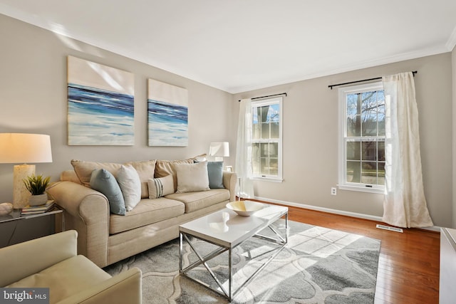 living room featuring visible vents, crown molding, baseboards, and hardwood / wood-style flooring