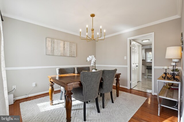 dining space featuring baseboards, a notable chandelier, wood finished floors, and ornamental molding